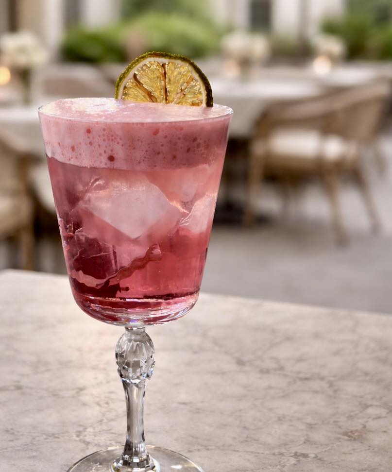 Cocktail rose signature servi en terrasse