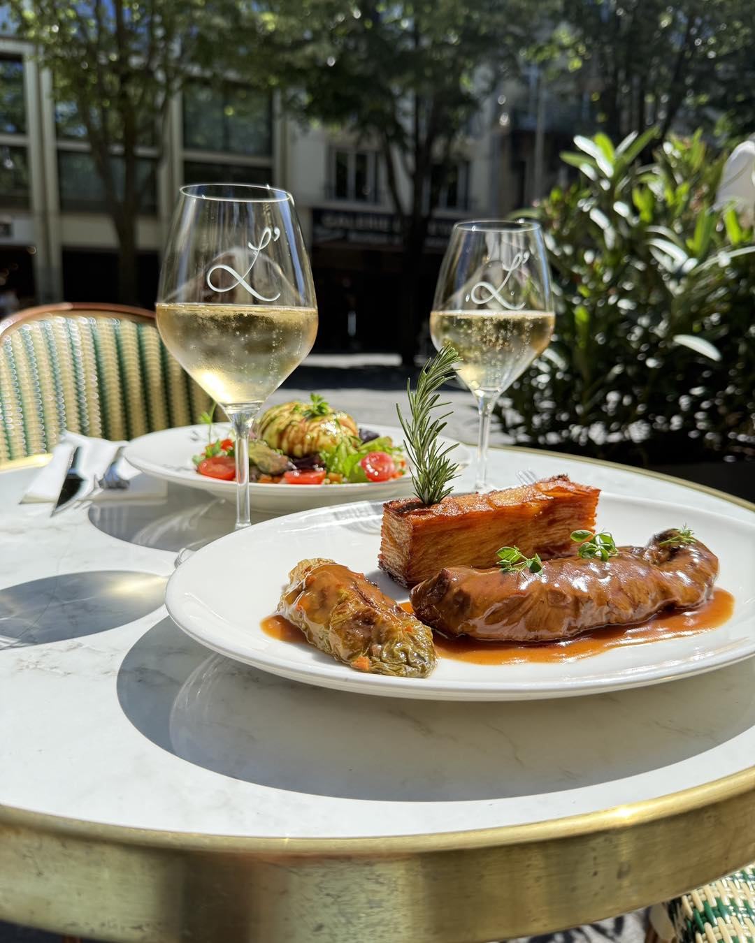 Plat de viande en terrasse avec deux coupes de champagne